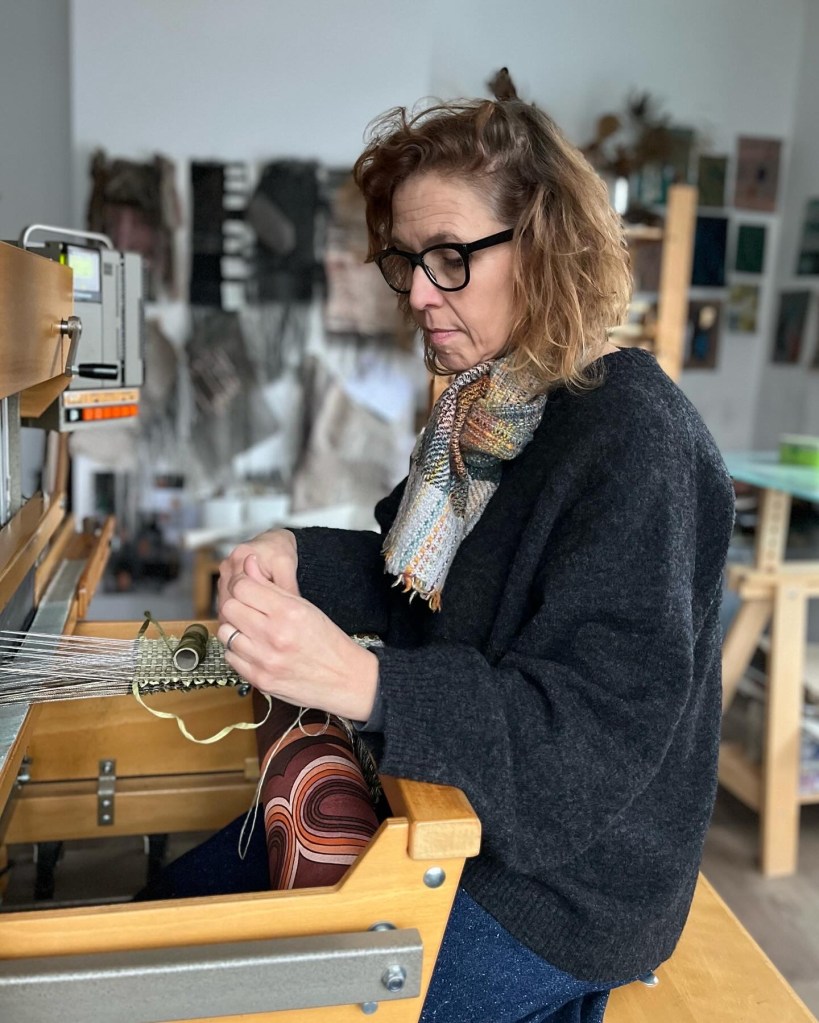 Veronica at work in the studio, sitting at her loom