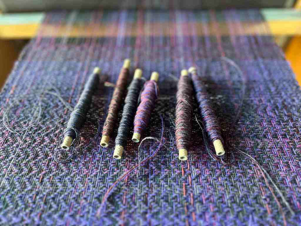 Commissioned handwoven scarf on the loom with bobbins