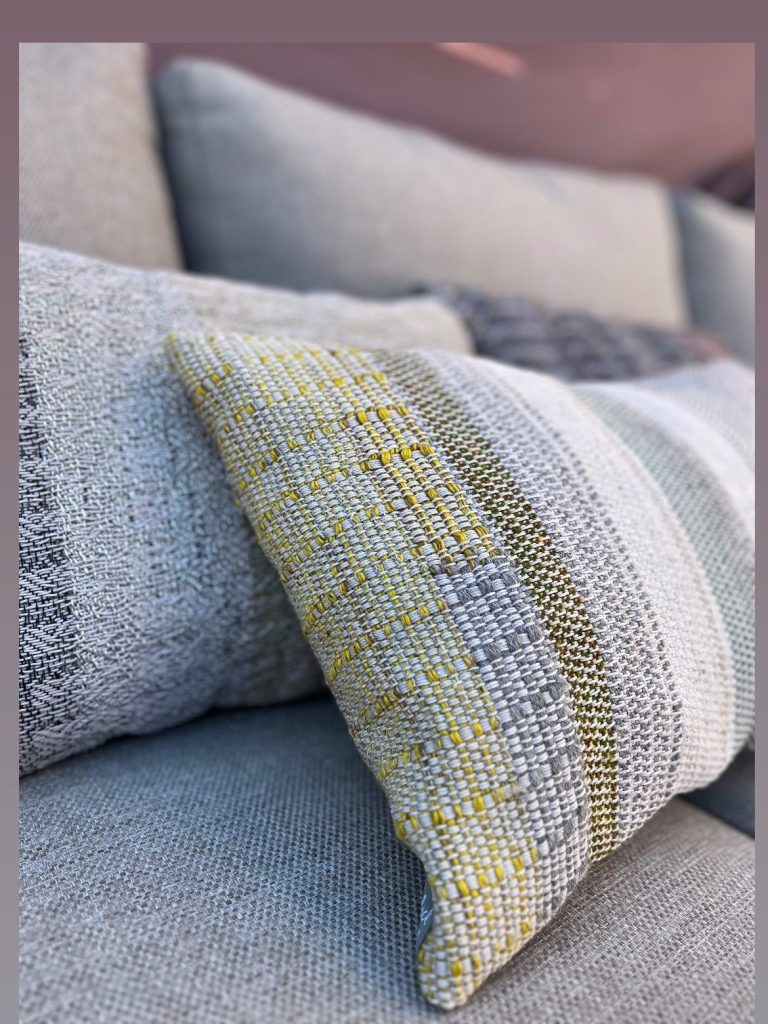 Close-up of woven cushions featuring a textured design in shades of grey, yellow, and white.